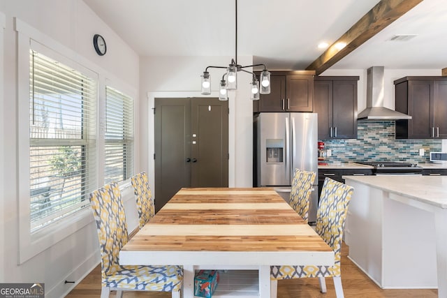 dining area with beamed ceiling, light hardwood / wood-style floors, and plenty of natural light