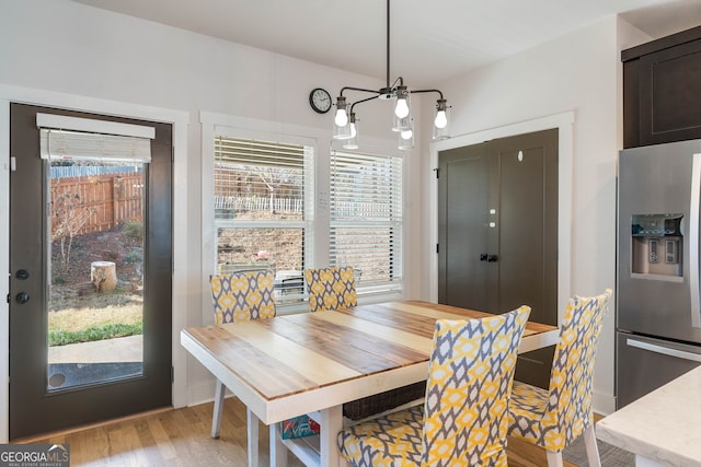 dining area with light hardwood / wood-style floors and an inviting chandelier