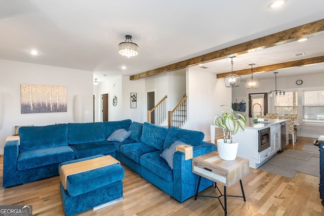 living room featuring beamed ceiling, an inviting chandelier, sink, and light hardwood / wood-style flooring