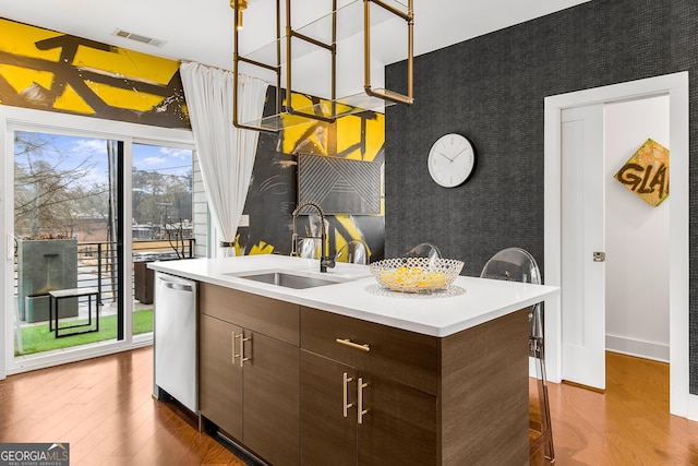 kitchen featuring dark brown cabinetry, sink, dishwasher, dark hardwood / wood-style floors, and an island with sink