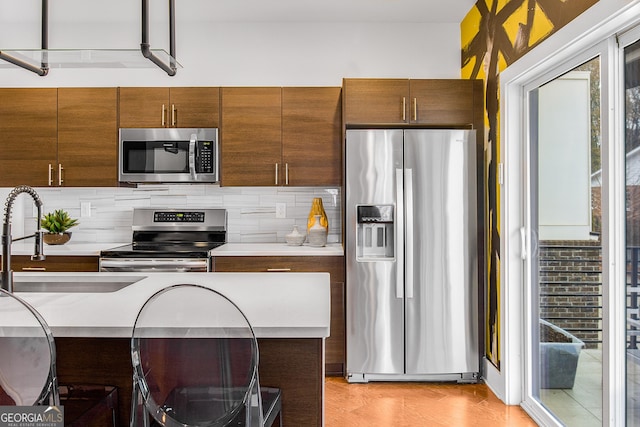 kitchen with a breakfast bar area, sink, appliances with stainless steel finishes, and tasteful backsplash