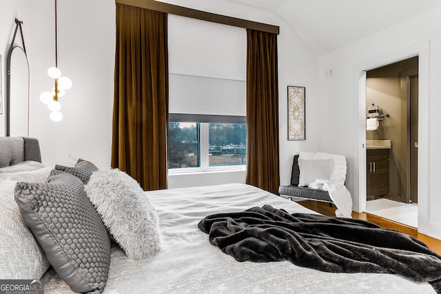 bedroom featuring light wood-type flooring, ensuite bathroom, and lofted ceiling