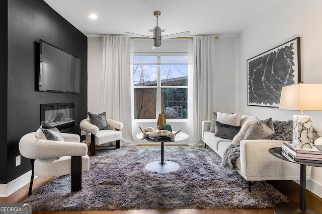 living room with ceiling fan, a fireplace, and hardwood / wood-style floors