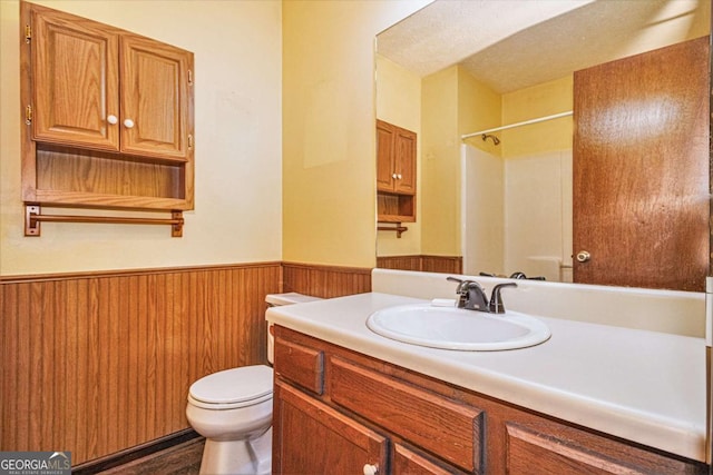 bathroom with vanity, toilet, walk in shower, and wooden walls