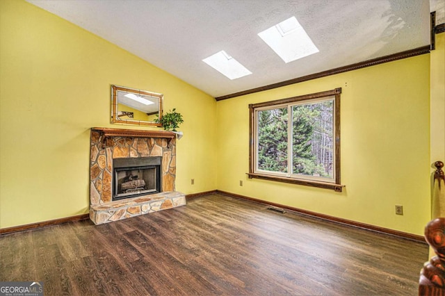 unfurnished living room with ornamental molding, hardwood / wood-style floors, a textured ceiling, a fireplace, and vaulted ceiling with skylight