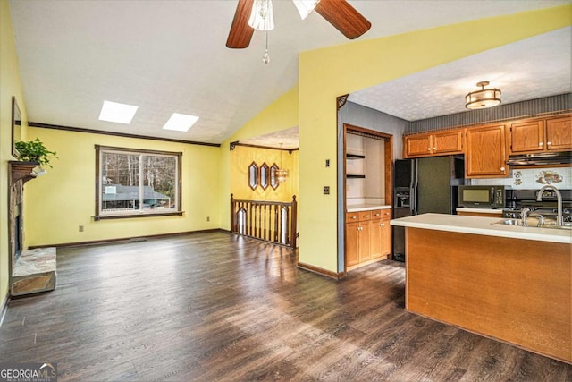 kitchen with black appliances, ceiling fan, dark hardwood / wood-style flooring, and vaulted ceiling with skylight