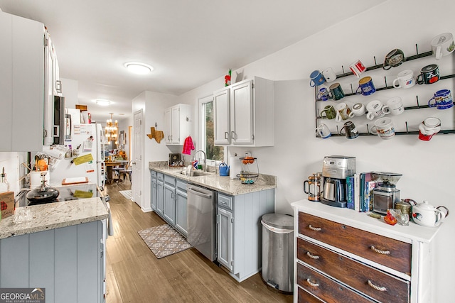 kitchen featuring sink, light stone counters, light hardwood / wood-style flooring, stainless steel dishwasher, and white fridge