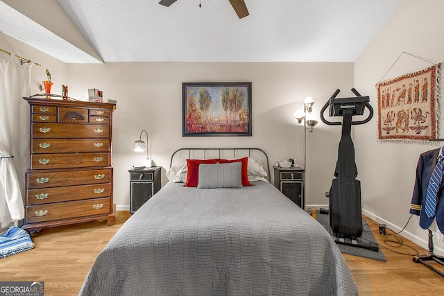 bedroom with hardwood / wood-style flooring, ceiling fan, lofted ceiling, and a textured ceiling