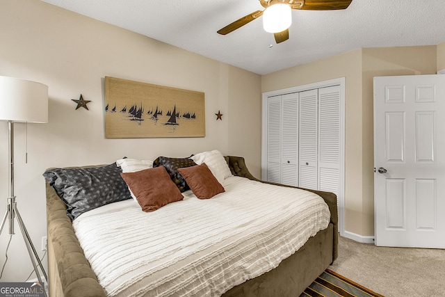 carpeted bedroom with ceiling fan, a textured ceiling, and a closet