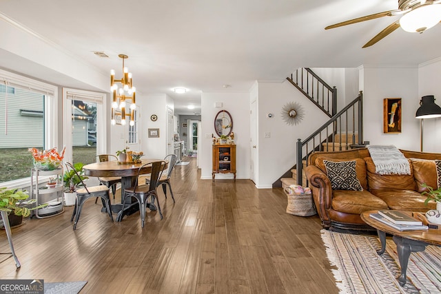 living room featuring ceiling fan with notable chandelier, crown molding, and dark wood-type flooring