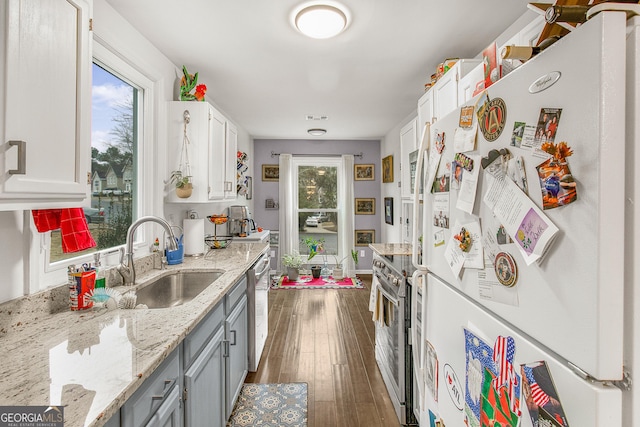 kitchen with light stone countertops, white cabinetry, sink, stainless steel appliances, and dark hardwood / wood-style flooring