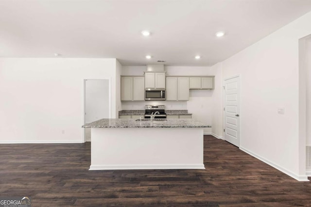 kitchen with a kitchen island with sink, dark hardwood / wood-style flooring, light stone counters, and appliances with stainless steel finishes