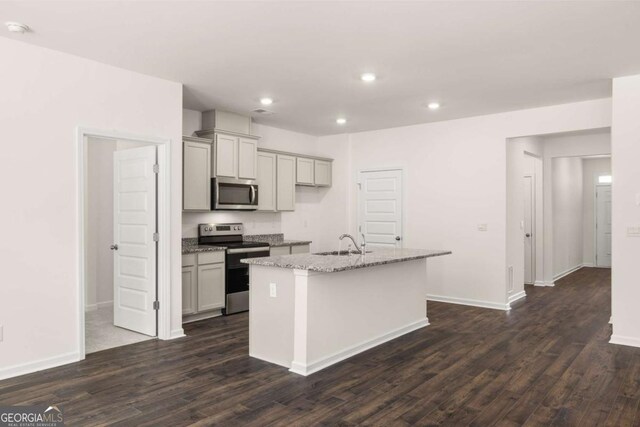 kitchen featuring sink, stainless steel appliances, gray cabinets, and an island with sink