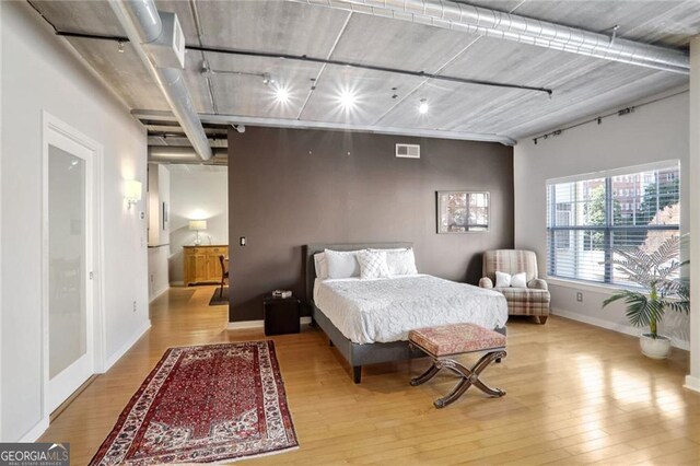 bedroom with rail lighting and light hardwood / wood-style flooring