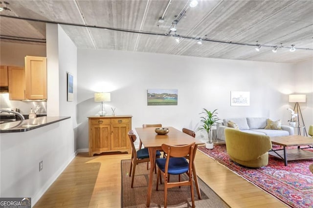 dining space featuring sink, light hardwood / wood-style floors, and rail lighting