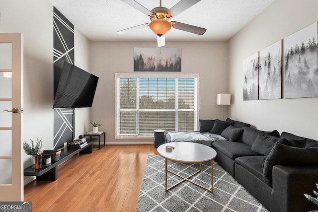 living room with ceiling fan, a textured ceiling, and wood-type flooring