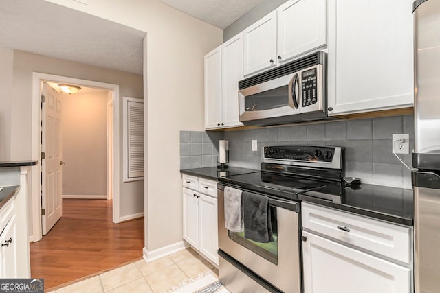 kitchen with dishwasher, sink, light wood-type flooring, white cabinetry, and a textured ceiling