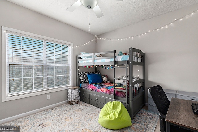 carpeted bedroom featuring ceiling fan and a textured ceiling