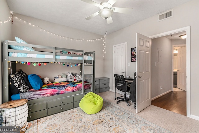 carpeted bedroom featuring ceiling fan, ensuite bathroom, and a textured ceiling