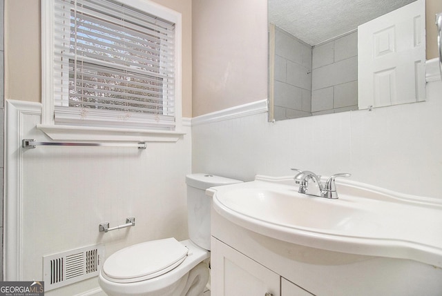 bathroom with a textured ceiling, vanity, and toilet