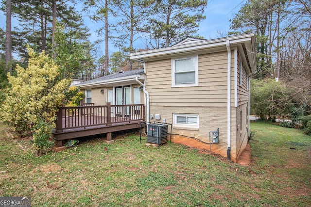 rear view of house with cooling unit, a yard, and a wooden deck