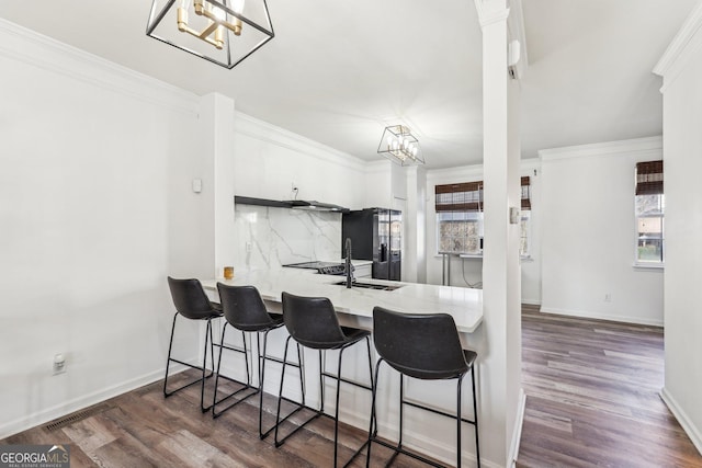 kitchen with kitchen peninsula, white cabinetry, dark hardwood / wood-style floors, and ornamental molding