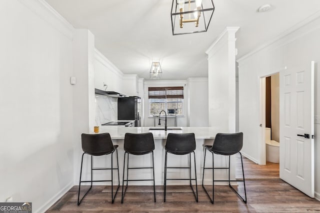 kitchen featuring white cabinets, a kitchen bar, kitchen peninsula, and sink