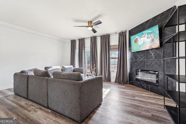 living room featuring a fireplace, wood-type flooring, ceiling fan, and ornamental molding