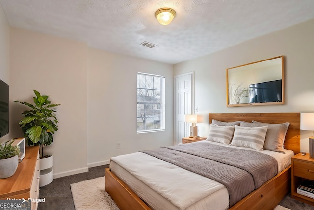 bedroom featuring dark colored carpet and a textured ceiling