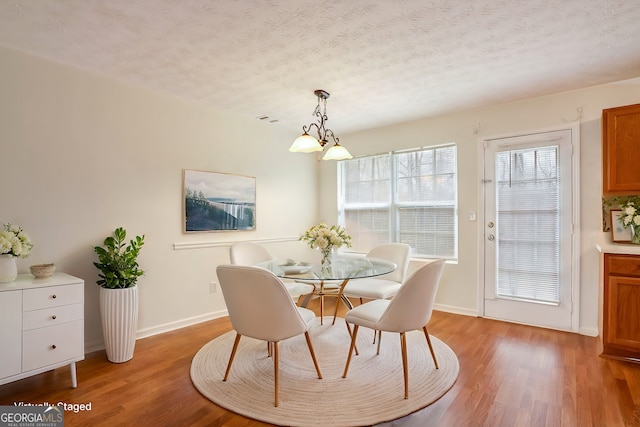 dining space featuring hardwood / wood-style flooring, a chandelier, and a textured ceiling