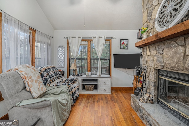 living room with vaulted ceiling, a fireplace, plenty of natural light, and light wood-type flooring