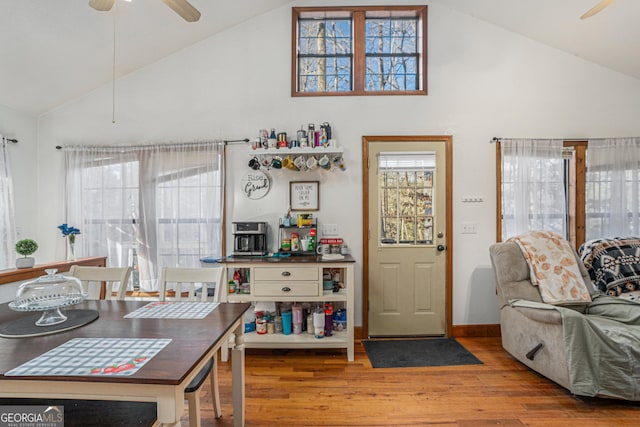 dining room with ceiling fan, wood-type flooring, high vaulted ceiling, and a wealth of natural light