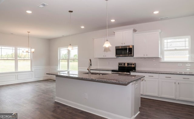 kitchen featuring a kitchen island with sink, white cabinets, sink, decorative light fixtures, and stainless steel appliances