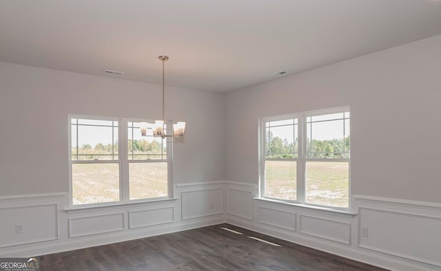 unfurnished dining area with a chandelier and dark hardwood / wood-style floors