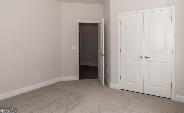 unfurnished bedroom with light carpet and a closet