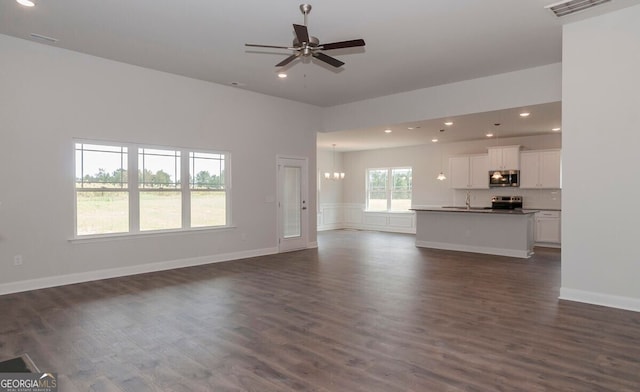 unfurnished living room featuring ceiling fan with notable chandelier, sink, and dark wood-type flooring