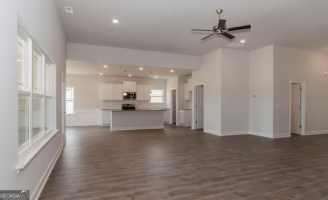 unfurnished living room with ceiling fan and dark wood-type flooring