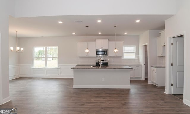 kitchen featuring a center island with sink, white cabinetry, and tasteful backsplash