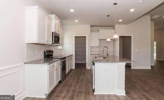 kitchen with a center island with sink, pendant lighting, white cabinets, and appliances with stainless steel finishes