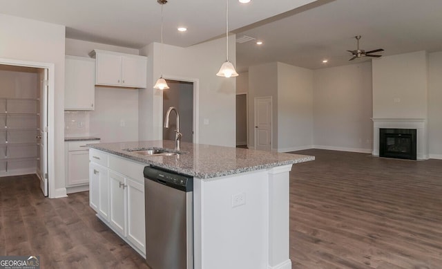 kitchen featuring light stone countertops, sink, stainless steel dishwasher, pendant lighting, and a kitchen island with sink