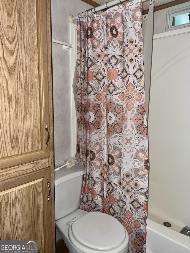 bathroom featuring toilet and curtained shower