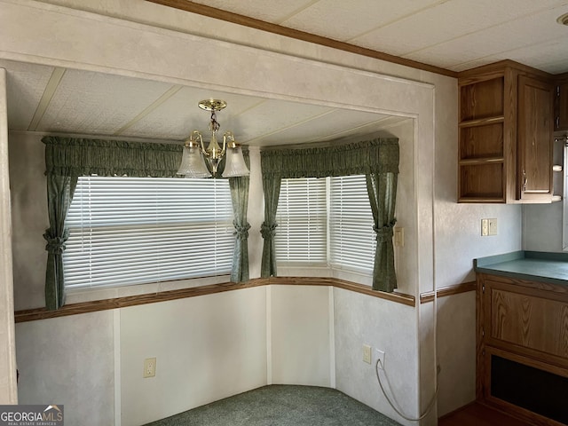 unfurnished dining area with carpet, an inviting chandelier, a wealth of natural light, and ornamental molding