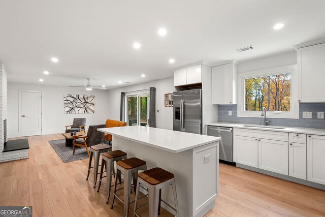 kitchen with white cabinets, sink, light wood-type flooring, and stainless steel appliances