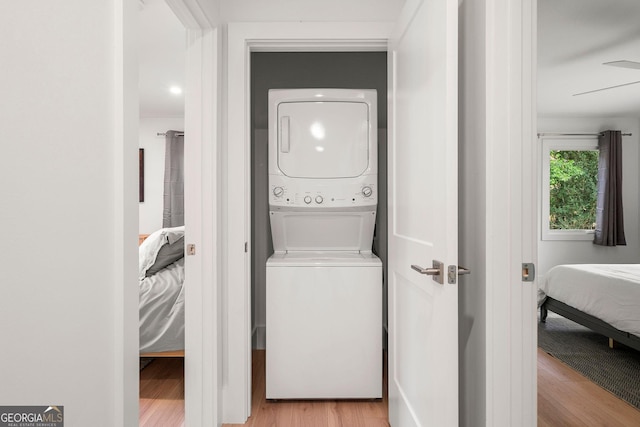 laundry area featuring stacked washing maching and dryer, ceiling fan, and light hardwood / wood-style floors