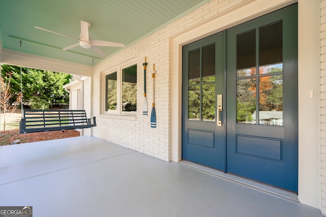 view of exterior entry featuring ceiling fan and a porch