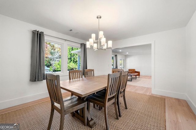 dining space with light hardwood / wood-style flooring and a notable chandelier