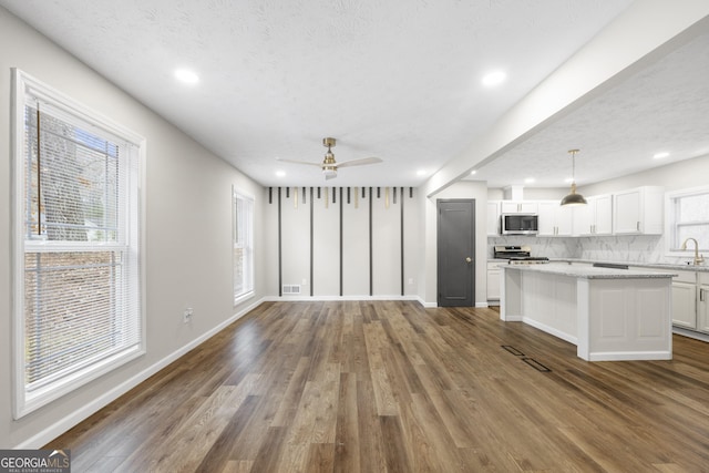 unfurnished living room featuring a textured ceiling, dark hardwood / wood-style floors, and plenty of natural light