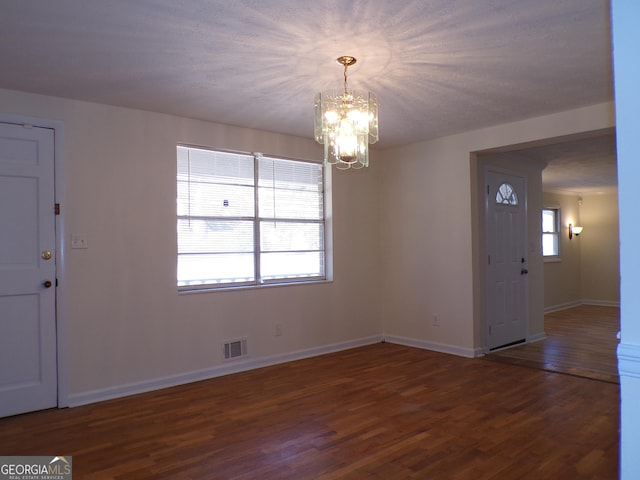 entrance foyer featuring a healthy amount of sunlight, dark hardwood / wood-style floors, and a notable chandelier