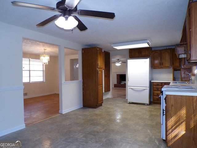 kitchen with ceiling fan with notable chandelier, white appliances, decorative light fixtures, and sink