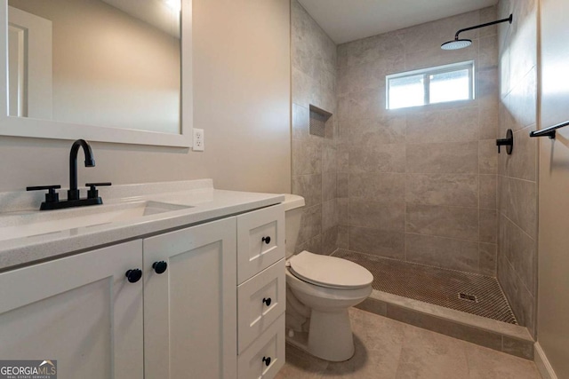 bathroom with tile patterned flooring, a tile shower, vanity, and toilet